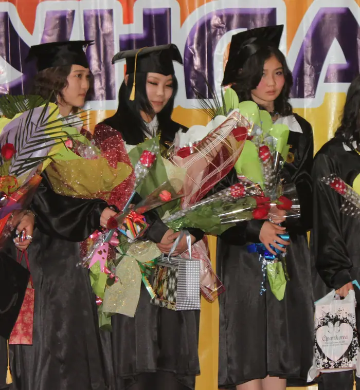 Graduates in gowns holding bouquets at the graduation ceremony